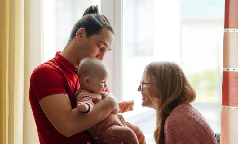 Parent talking and holding their baby in the morning.