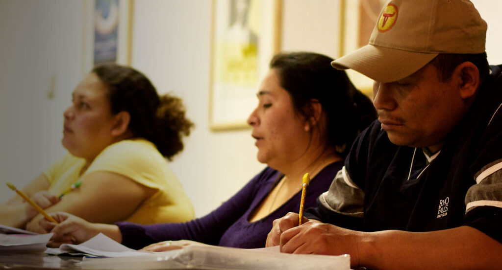 Two female Latinas and one Latino male attend a workshop on empowering immigrants to know their rights.